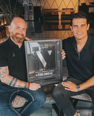 Dos hombres sentados, sosteniendo una placa enmarcada que celebra el logro de más de 500.000 euros en ventas digitales.